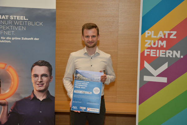 Photograph of Florian Stögmüller holding the Adolf-Adam-Award of 2023